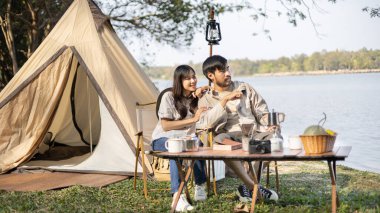 Couple camping for the weekend in the woods near the river, Camping Holiday In Countryside, Camping for the day and recreational activities amidst nature and relaxation, Outdoor leisure activities.