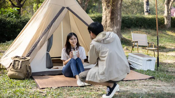 Camping for the weekend in the woods near the river, Relaxation activities for young couples, Woman using mobile phone to take a selfie with her boyfriend, Young couple outdoor leisure activities.