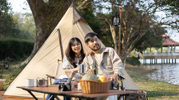 Couple camping for the weekend in the woods near the river, Camping Holiday In Countryside, Camping for the day and recreational activities amidst nature and relaxation, Outdoor leisure activities.