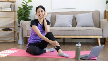 Beautiful healthy woman practicing yoga, Stretch or warm up before exercising, Calming the mind and meditating in her living room, Dumbbells and a protein shake or bottle of water, Healthy exercise.