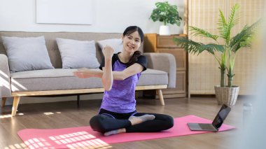 Beautiful healthy woman practicing yoga, Stretch or warm up before exercising, Calming the mind and meditating in her living room, Dumbbells and a protein shake or bottle of water, Healthy exercise.