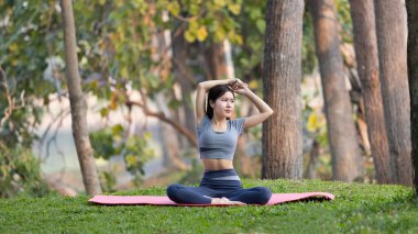 Ormanda yoga yapan Asyalı kadın, meditasyon ve nefes egzersizleri, dikkat eksikliğini tedavi edin ve zihninizi sakin, sağlıklı egzersiz, farkındalık, Homeopati, Park yogası için eğitin..