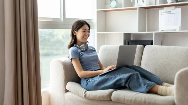 Asyalı Kadın Elinde Dizüstü Bilgisayarla Kanepede Oturuyor Dizüstü Bilgisayara Bakıyor — Stok fotoğraf