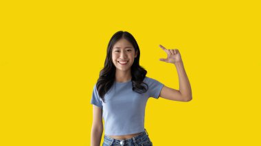 Asian woman with holding copyspace imaginary on the palm to insert an ad, Showing copyspace pointing, Showing her hand to present something on yellow background.