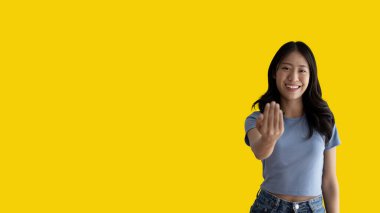 Women beckoning or inviting them to pay attention, Suggest to click or apply with me, Giving assistance and acceptance, Calling with one finger, Come and get me, Woman on yellow background.