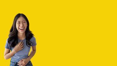 Asian woman laughing happily on yellow background, Happiness through laughter, Funny, Copy space, Portrait, Advertising text area, Isolated on yellow background.