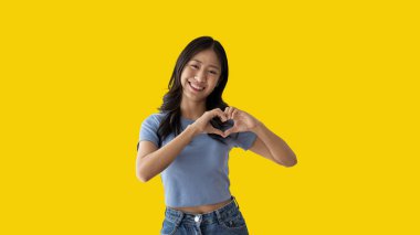 Asian young woman with bright smile making heart symbol shape with hands, Symbol of love and romance, Give each other cuteness and create smiles for each other, Positive thinking concept.