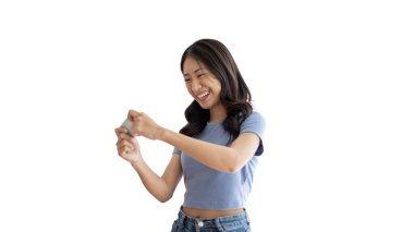 Cep telefonuyla oyun oynayan, kulaklık takan, hafta sonları oturma odasındaki kanepede oyun oynayan, evinde dinlenen, rahat alan, cep telefonu kullanan Asyalı bir kadın..