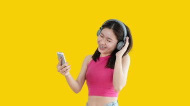 Genç Asyalı kadın kulaklıkla müzik dinlemekten mutluydu. Kız en sevdiği müziği dinlemekten ve müziğin ritmiyle sallanmaktan keyif alıyordu. Stres atma, hayatta mutluluk..