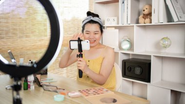 Sosyal medya etkisine sahip güzel bir kadın, video blogunu canlı yayınladığı için seyirciyi selamlıyor. Güzellik blogcuları kavramında makyaj ve kozmetik, çevrimiçi iş dünyasının nasıl kullanılacağını gösteriyor..