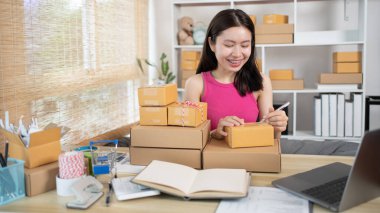 Kadın, bilgilere göre nakliyeye hazırlanmak için müşteri bilgilerini ve adreslerini not defterine ya da posta kutusuna yazıyor. Paketleme kutusu, çevrimiçi satış, serbest çalışma..