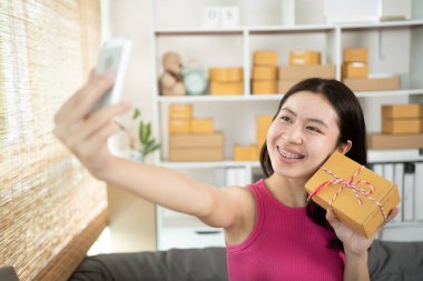 Kadın telefonuyla ürünlerle ya da selfielerle fotoğraf çekiyor, kimlik doğrulaması ya da sipariş onayı, iş stili evde çalışıyor, evde çalışıyor ve işletme sahibi oluyor..