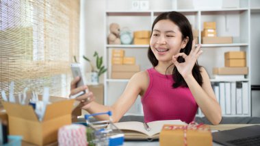 Kadın telefonuyla ürünlerle ya da selfielerle fotoğraf çekiyor, kimlik doğrulaması ya da sipariş onayı, iş stili evde çalışıyor, evde çalışıyor ve işletme sahibi oluyor..