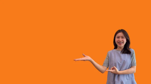ヤシの上に想像上のコピースペースを保持しているアジアの女性は 広告を挿入します コピースペースを示す オレンジの背景に何かを提示するために彼女の手を示す — ストック写真