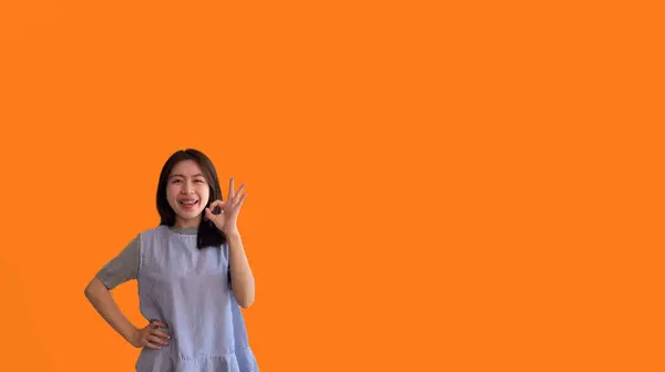 亚洲的年轻女子 背景橙色 手握手签 好的符号 按指示做 服从命令 接受一切条件 — 图库照片
