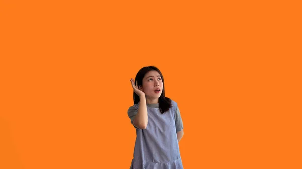 オレンジの背景 ゴシップ リスニング オレンジの背景スタジオの肖像画に隔離されたアジアの女性の盗聴や聴覚秘密の会話 — ストック写真