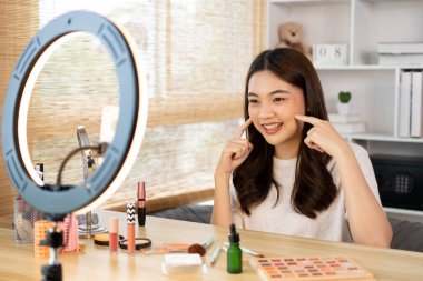 Sosyal medya etkisine sahip güzel bir kadın, video blogunu canlı yayınladığı için seyirciyi selamlıyor. Güzellik blogcuları kavramında makyaj ve kozmetik, çevrimiçi iş dünyasının nasıl kullanılacağını gösteriyor..