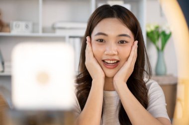 Sosyal medya etkisine sahip güzel bir kadın, video blogunu canlı yayınladığı için seyirciyi selamlıyor. Güzellik blogcuları kavramında makyaj ve kozmetik, çevrimiçi iş dünyasının nasıl kullanılacağını gösteriyor..