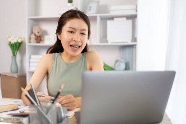 Asyalı kız öğrencilerin sohbet etmesi ya da bilgi alışverişinde bulunması dizüstü bilgisayar video çağrısı, kablosuz eğitim sistemi, öğretmenler ve sınıf arkadaşlarıyla konuşmaları, çevrimiçi öğrenme, kendi evinizde eğitim.