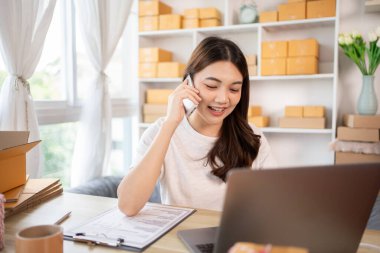 İş sahibi telefonda bir müşteriyle konuşuyor. İş sahibi dizüstü bilgisayardan, paketlemeden, teslimattan, paketlemeden ve nakliyattan emir alıyor..