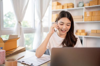 İş sahibi telefonda bir müşteriyle konuşuyor. İş sahibi dizüstü bilgisayardan, paketlemeden, teslimattan, paketlemeden ve nakliyattan emir alıyor..