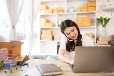 İş sahibi telefonda bir müşteriyle konuşuyor. İş sahibi dizüstü bilgisayardan, paketlemeden, teslimattan, paketlemeden ve nakliyattan emir alıyor..