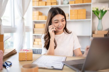 İş sahibi telefonda bir müşteriyle konuşuyor. İş sahibi dizüstü bilgisayardan, paketlemeden, teslimattan, paketlemeden ve nakliyattan emir alıyor..