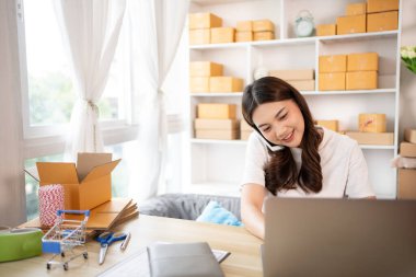 İş sahibi telefonda bir müşteriyle konuşuyor. İş sahibi dizüstü bilgisayardan, paketlemeden, teslimattan, paketlemeden ve nakliyattan emir alıyor..