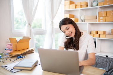 İş sahibi telefonda bir müşteriyle konuşuyor. İş sahibi dizüstü bilgisayardan, paketlemeden, teslimattan, paketlemeden ve nakliyattan emir alıyor..