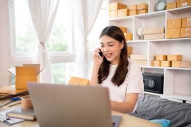 Çevrimiçi alışveriş şirketi sahibi telefonda teslimat adresi ve teslimat çizelgesini, KOBİ girişimcisinin online alışverişini, paketleme kutusunu, çevrimiçi satışı ve serbest çalışma programını yazmak için bir müşteriyle konuşuyor..