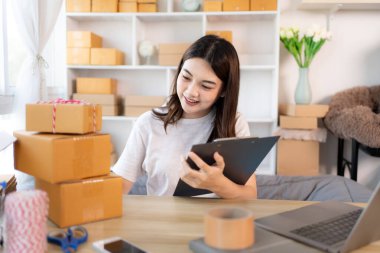 Çevrimiçi satış işlerinde, küçük işletme sahipleri envanterleri kontrol ederek müşterilere uygun teslimat için hazırlıyorlar, Evden çalışmak: E-ticaret operasyonlarını yönetmek. 