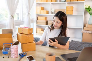 Çevrimiçi satış işlerinde, küçük işletme sahipleri envanterleri kontrol ederek müşterilere uygun teslimat için hazırlıyorlar, Evden çalışmak: E-ticaret operasyonlarını yönetmek. 
