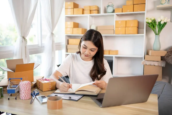 Woman Writing Customer Details for Shipping in Home Office, Packing Box and Writing Customer Information for Efficient Shipping, E-Commerce and Online Selling Concept.