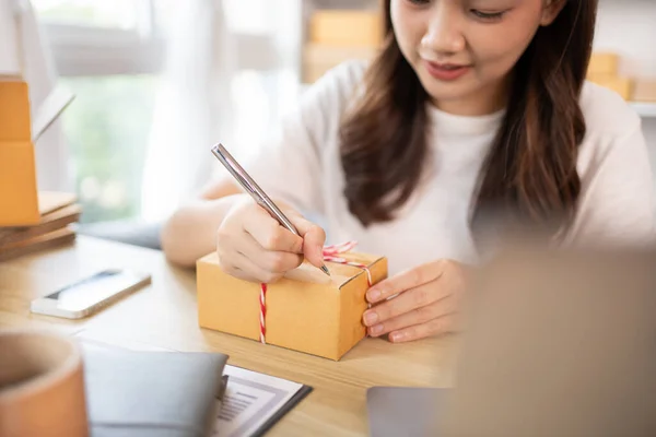 Woman Writing Customer Details for Shipping in Home Office, Packing Box and Writing Customer Information for Efficient Shipping, E-Commerce and Online Selling Concept.