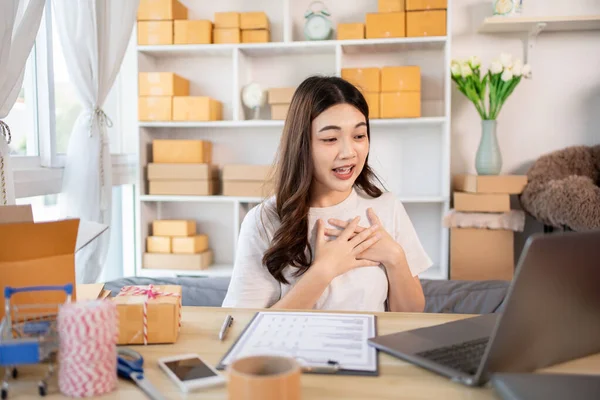 Happy Woman Celebrating Order from Internet Customer: New Business Style at Home, Online Selling, Young Entrepreneur\'s Success: Work-from-Home SME Owner Thrives in Online Sales, Packing Box.