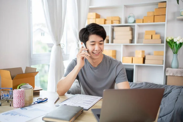 Online shopping business owner is talking on the phone with a customer to jot down the delivery address and delivery schedule, SME entrepreneur online shopping, Packaging box Sell online, Work freelance.