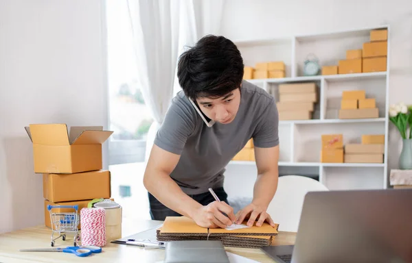 Man Writing Customer Details for Shipping in Home Office, Packing Box and Writing Customer Information for Efficient Shipping, E-Commerce and Online Selling Concept.