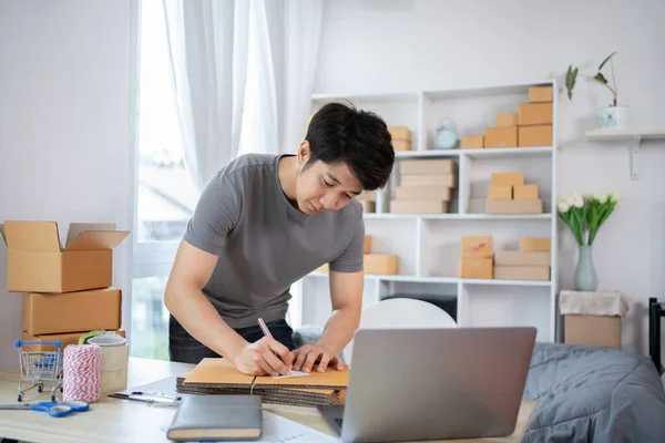 Man Writing Customer Details for Shipping in Home Office, Packing Box and Writing Customer Information for Efficient Shipping, E-Commerce and Online Selling Concept.
