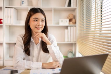 Woman using laptop to work or do homework at home with smiling face in her office, Creating happiness at work with a smile, Live performance or vdo call with laptop, Work from home.