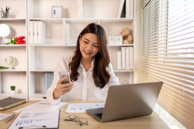 Genç kız üniversite öğrencileri telefonda konuşur ve aynı zamanda ev ödevlerini yapar, mutlu ev yaşamları, evde çalışırlar..