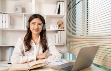 Woman using laptop to work or do homework at home with smiling face in her office, Creating happiness at work with a smile, Live performance or vdo call with laptop, Work from home.