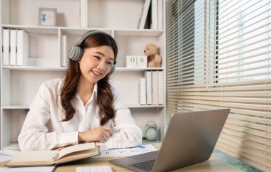 Woman using laptop to work or do homework at home with smiling face in her office, Creating happiness at work with a smile, Live performance or vdo call with laptop, Work from home.