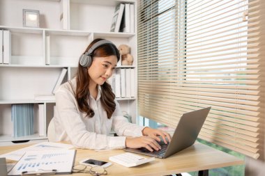 Woman using laptop to work or do homework at home with smiling face in her office, Creating happiness at work with a smile, Live performance or vdo call with laptop, Work from home.
