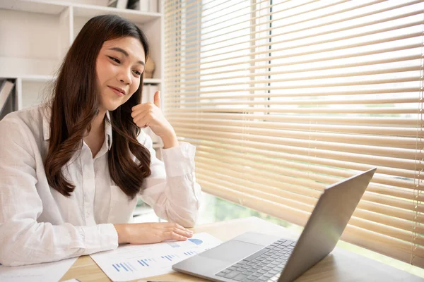 stock image Young Asian woman greets his friends or colleague in a live video with a smile on his face, Online communication , Vdo call via laptop, Social distancing, Internet learning.