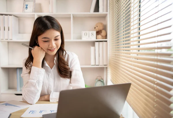 stock image Woman using laptop to work or do homework at home with smiling face in her office, Creating happiness at work with a smile, Live performance or vdo call with laptop, Work from home.