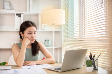 Woman using laptop to work or do homework at home with smiling face in her office, Creating happiness at work with a smile, Live performance or vdo call with laptop, Work from home.
