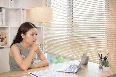 Woman using laptop to work or do homework at home with smiling face in her office, Creating happiness at work with a smile, Live performance or vdo call with laptop, Work from home.