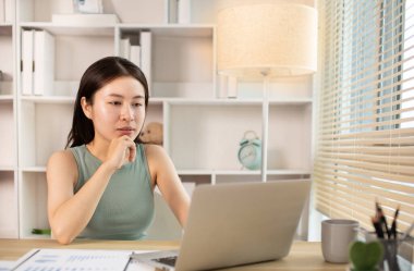 Woman using laptop to work or do homework at home with smiling face in her office, Creating happiness at work with a smile, Live performance or vdo call with laptop, Work from home.