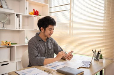 Genç adam cep telefonunda gülümseyen yüzüyle sohbet ya da mesaj yazıyor, Smartphone 'da gülen yüz, dijital iletişim, internet ağının akıllı telefonu aracılığıyla sohbet mesajı yazıyor..