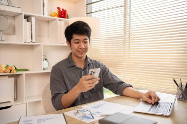Genç adam cep telefonunda gülümseyen yüzüyle sohbet ya da mesaj yazıyor, Smartphone 'da gülen yüz, dijital iletişim, internet ağının akıllı telefonu aracılığıyla sohbet mesajı yazıyor..